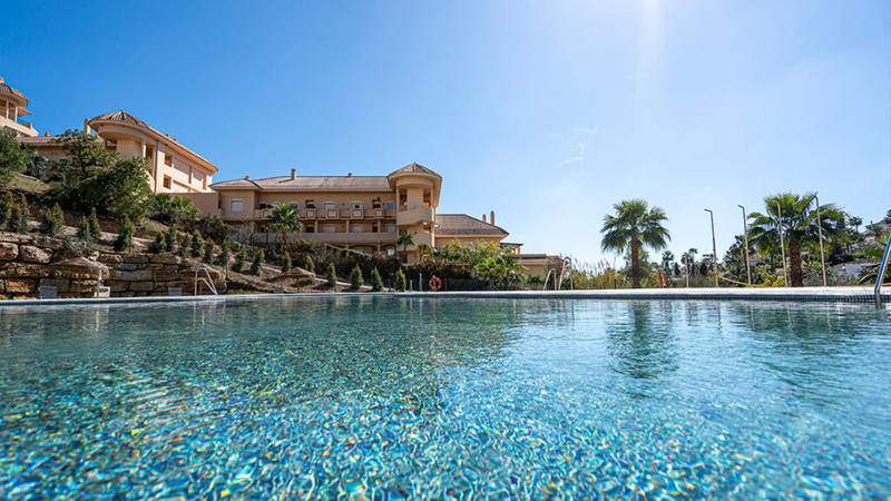 Be Aloha – Marbella - luksuriøst utendørs svømmebasseng med terrasse og mediterrane boliger under klar blå himmel