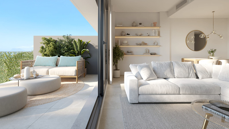Blue Wave – Manilva - lys åpen stue med hvit sofa, innebygde hyller og sømløs terrasseadgang med havutsikt