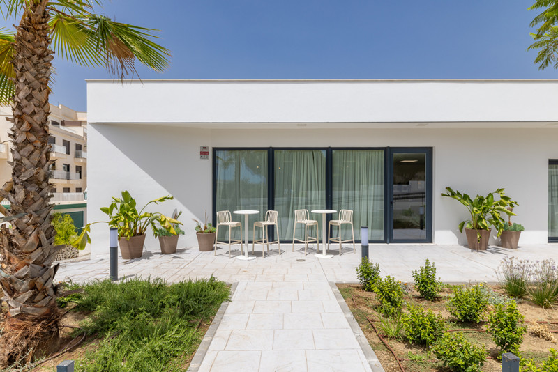 Cala Serena Village – La Cala de Mijas - moderne hvit terrasse med barstoler, brolagt sti og frodig hageplan