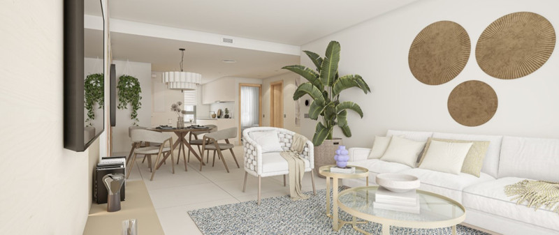 Grand Bay Leilighets – Manilva - lys åpen stue og spisestue med hvit sofa, lenestol og tropiske planter