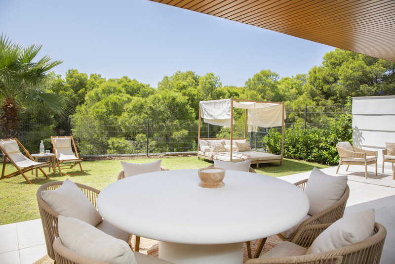 Higueron West – Fuengirola - skyggerik terrasse med rundt hvitt spisebord, kurvstoler, hage og baldakin-dagseng omgitt av grønt