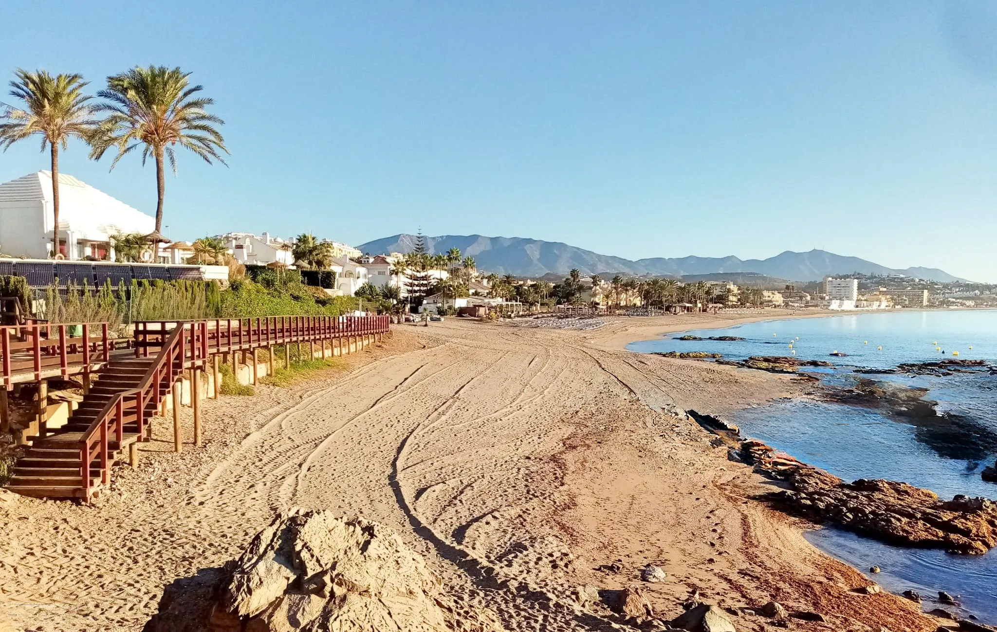 La Cala de Mijas kystlinje med strand, palmer og Sierra de Mijas-fjellene