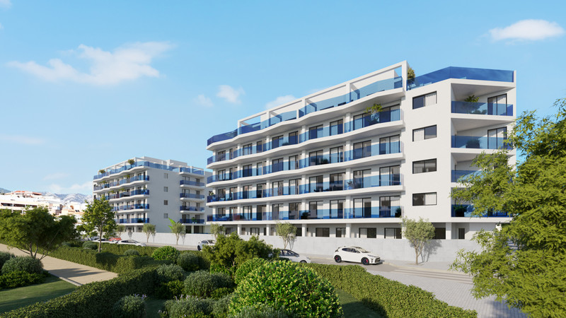 Laguna One – Las Lagunas - moderne hvit boligfasade med blå glassbalkonger, velstelt hage og parkerte biler i forgrunnen