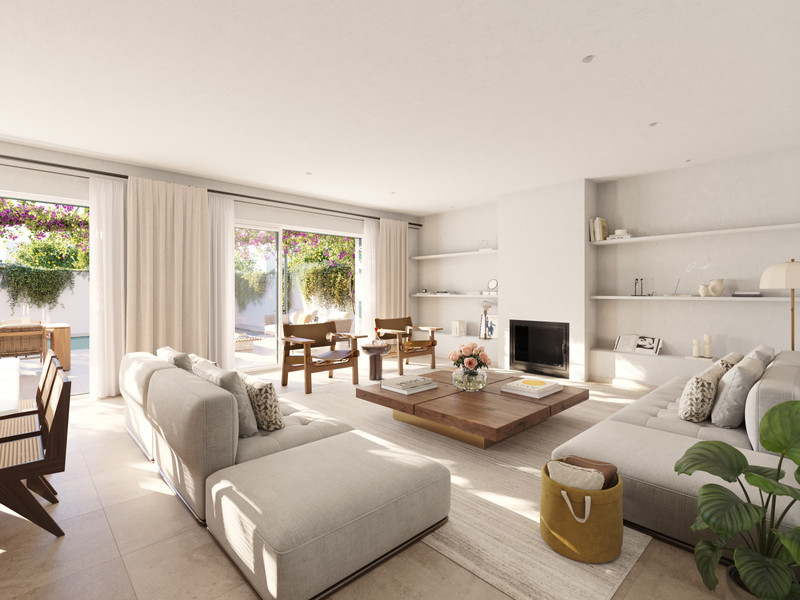 Las Villas–Sotogrande – Sotogrande - lyst åpent oppholdsrom med stor sofa, peis og skyvedører fra gulv til tak mot hagen