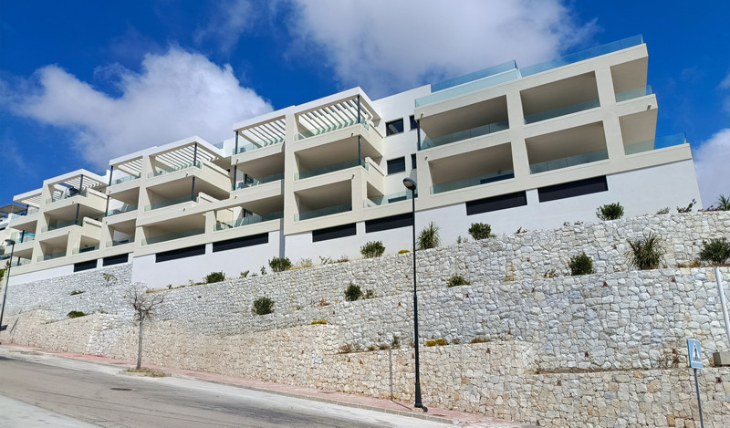 Mane Residences – Benalmadena - moderne hvit fasade med terrasserte balkonger på skråning med steinmur