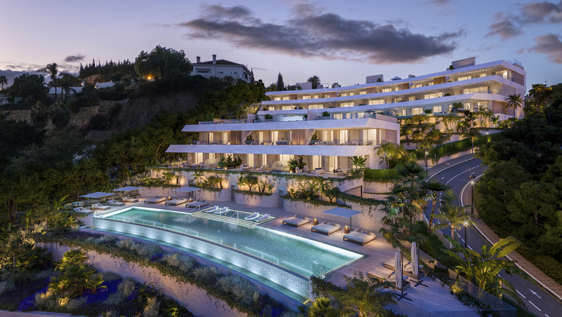 Solenne – Benahavís - luxury white hillside apartment complex with illuminated infinity pool at dusk