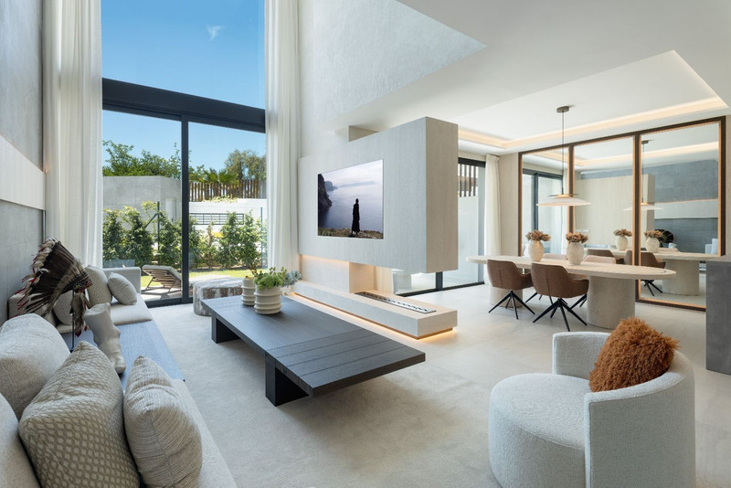 The List Rio Real – Marbella - lys åpen stue med dobbel takhøyde, peis, TV-vegg og spiseplass