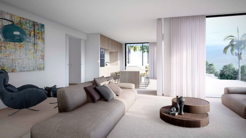 Villa Ana – Artola - lyst åpent stueplan med beige sofa, rundt sofabord, tynne gardiner og havutsikt med palmetrær