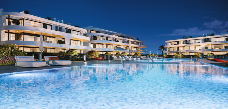 Naya Residences – Atalaya - luxury illuminated swimming pool and white modern apartment facades at dusk