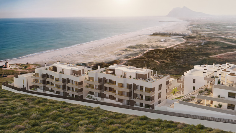 Paraiso Beach – Townhouses – La Línea - aerial view of white modern residential complex with sea, sandy beach and mountain backdrop